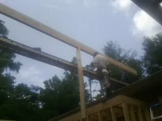 Carpenter setting a ridge beam over a new addition frame — Ice Dam Removal by Roofing Brothers in Sylvan Beach