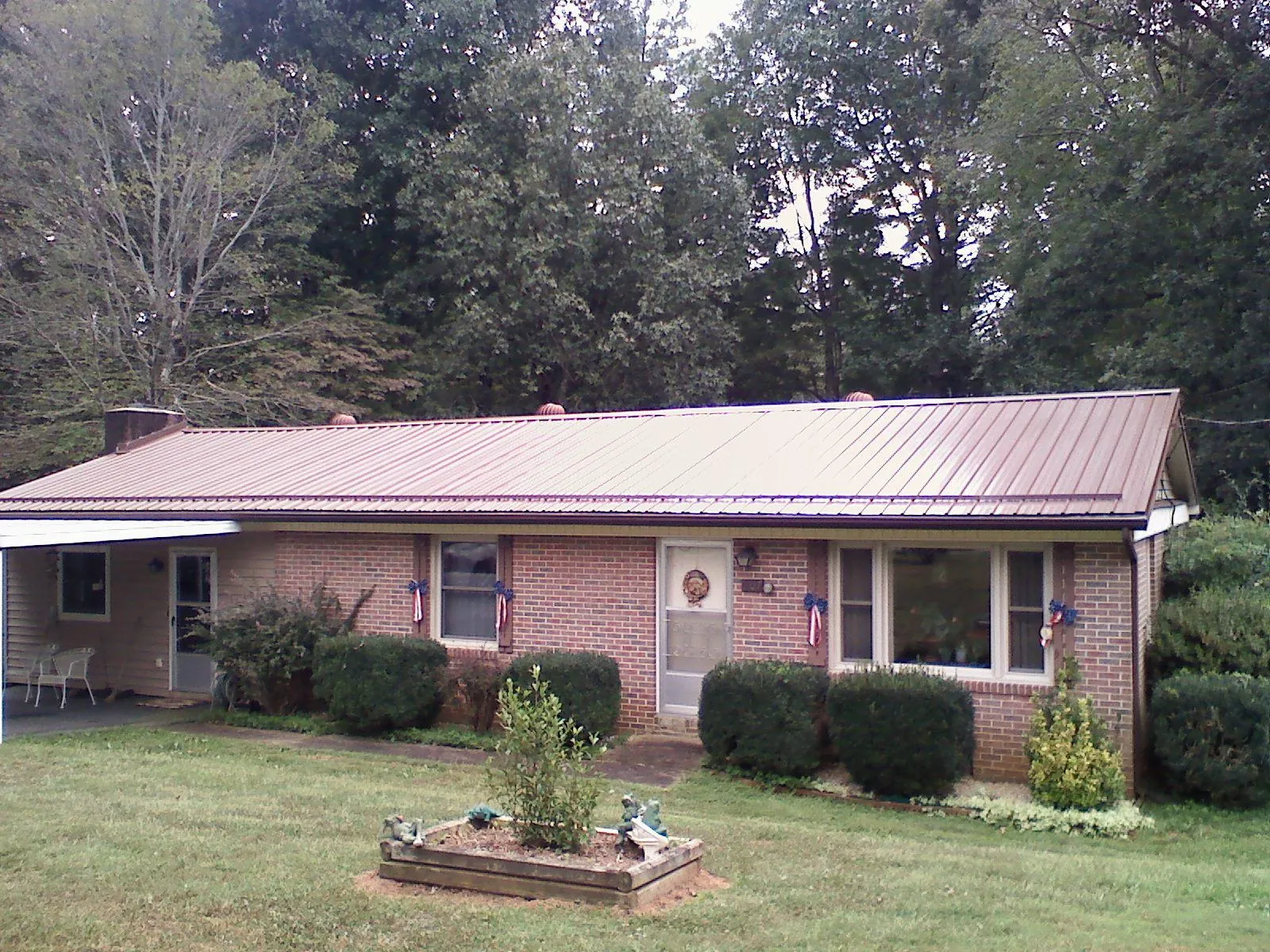 Bronze metal roof on a brick ranch home with a carport in Sylvan Beach