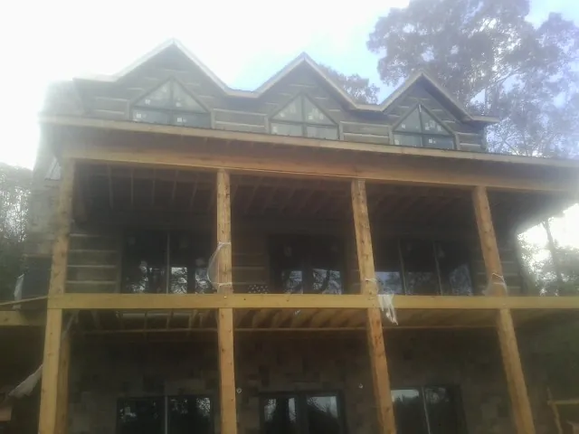 Dormers and porch framing on a large log home under construction — Roof Coating work by our crew in Sylvan Beach