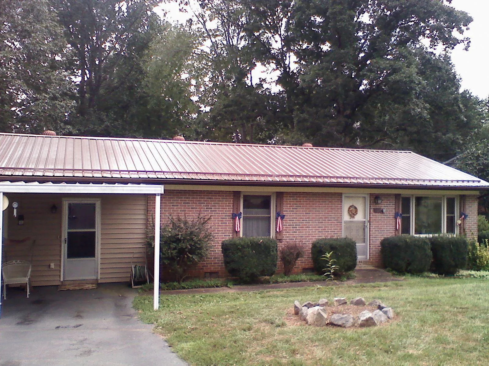 Bronze metal roof and carport on a brick ranch home — Roof Repair work by our crew in Sylvan Beach